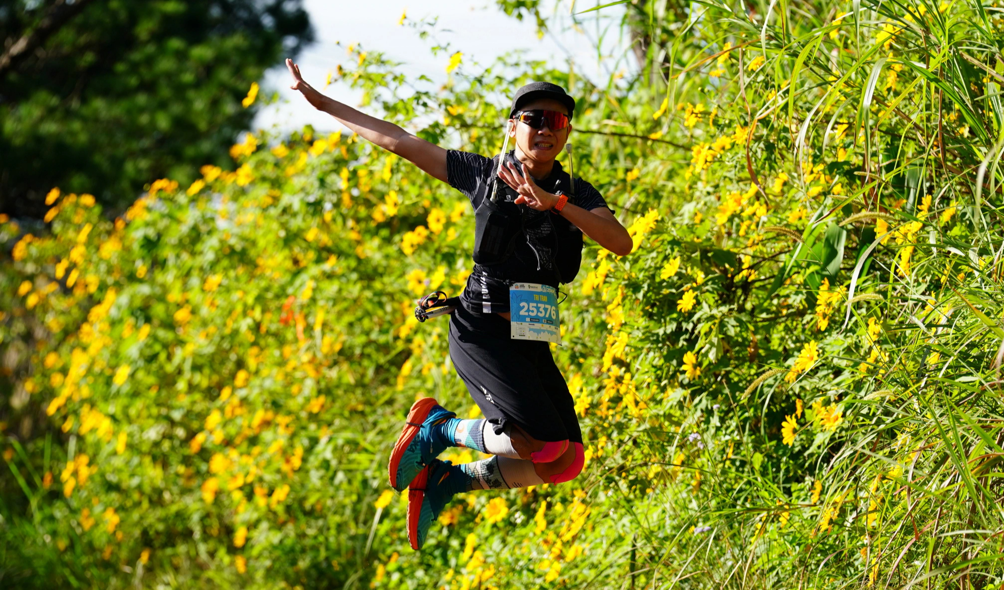 A runner poses beside yellow wild sunflowers at Lamdong Trail 2024; historical photograph.